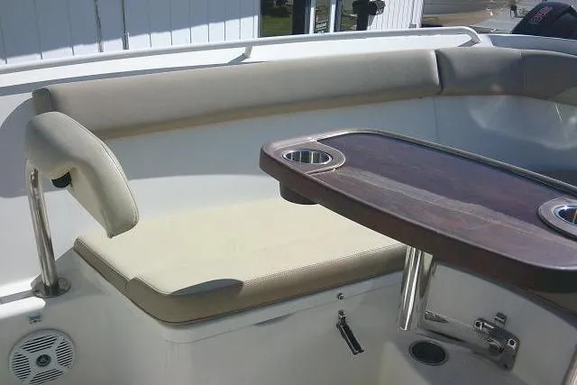 Slide: The Image of 2017 Sailfish 240 CC boat interior with cushioned seating and wooden table. - 17