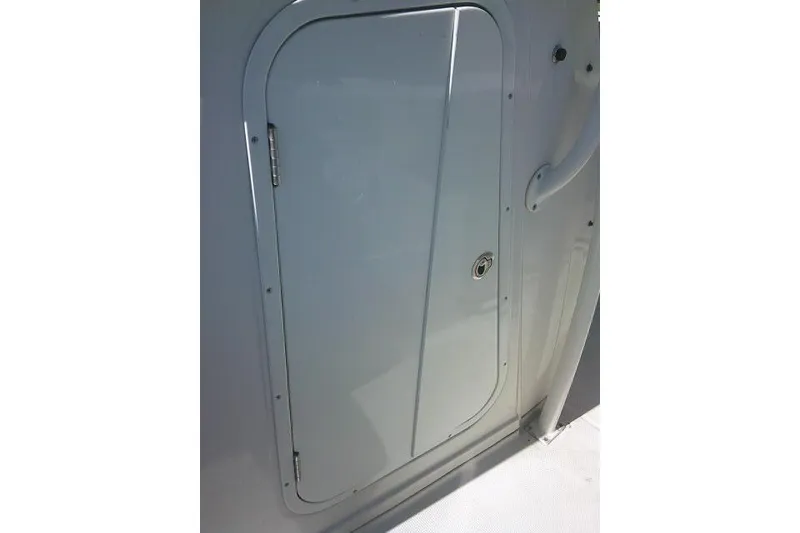 Slide: The Image of 2017 Sailfish 240 CC boat compartment door, featuring a sleek design and secure lock. - 21