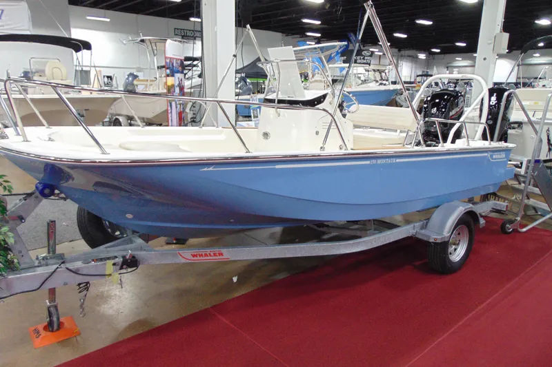 The Image of 2026 Boston Whaler 170 Montauk boat displayed indoors on a trailer. - 1