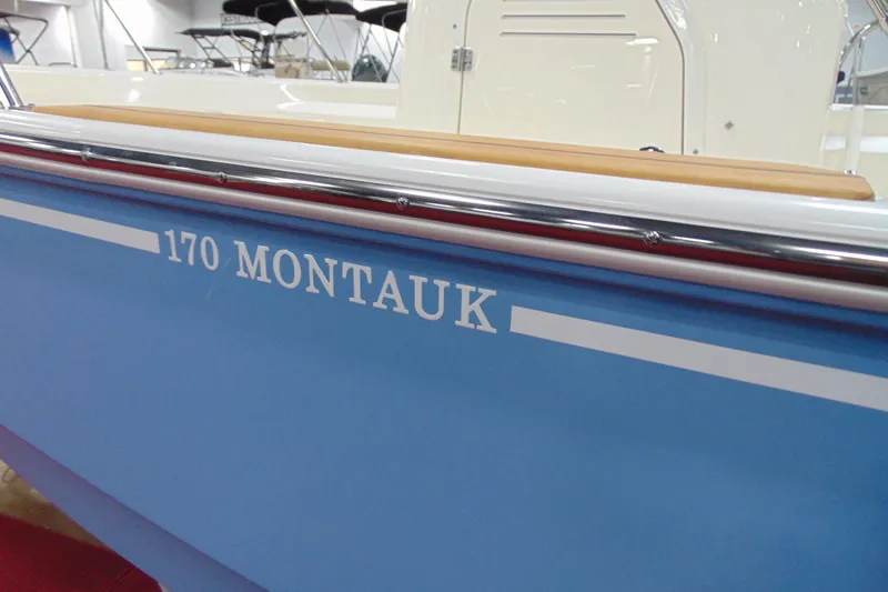 Slide: The Image of 2026 Boston Whaler 170 Montauk boat side view with blue hull and white lettering. - 5