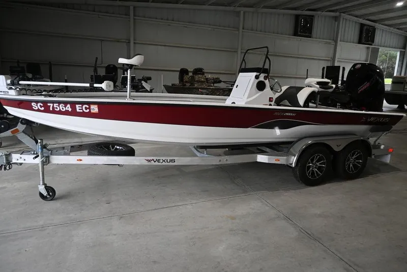 The Image of 2023 Vexus AVX2180CC boat on trailer in a garage setting. - 1