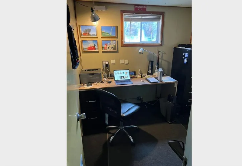 Slide: The Image of Small office with desk, laptop, and framed lift boat photos on the wall. - 11