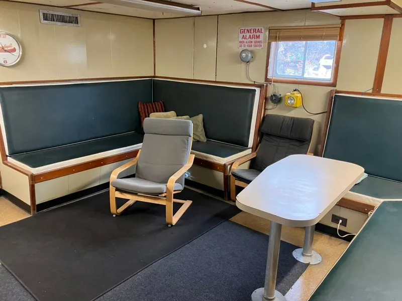 Slide: The Image of Interior of a 1981 custom lift boat with seating, table, and general alarm sign. - 14