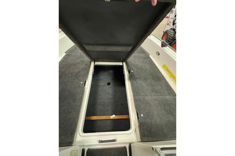 Slide: The Image of Open storage compartment in 2012 Skeeter WX2100 boat, featuring carpeted interior. - 17