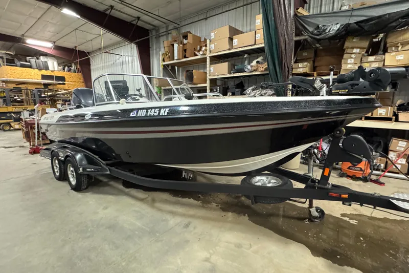 Slide: The Image of 2012 Skeeter WX2100 boat in a warehouse, on a trailer, surrounded by shelves. - 2