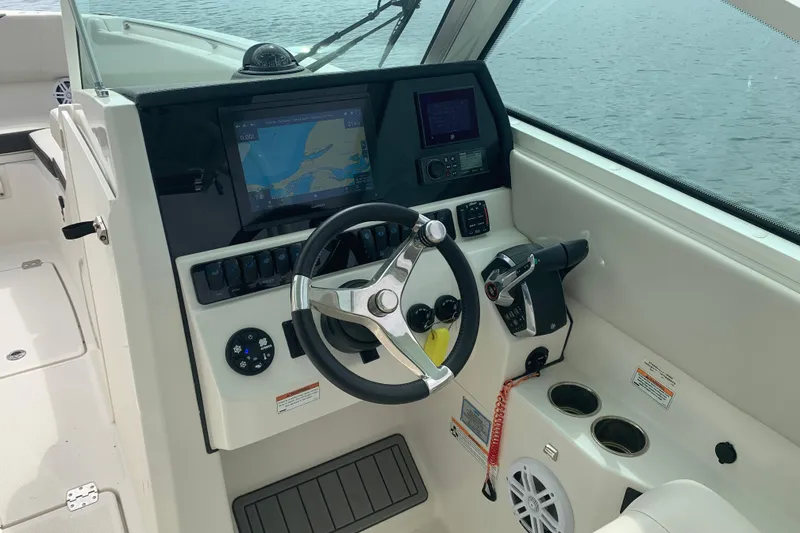Slide: The Image of 2023 Sailfish 276 DC boat cockpit with steering wheel, navigation display, and controls. - 24