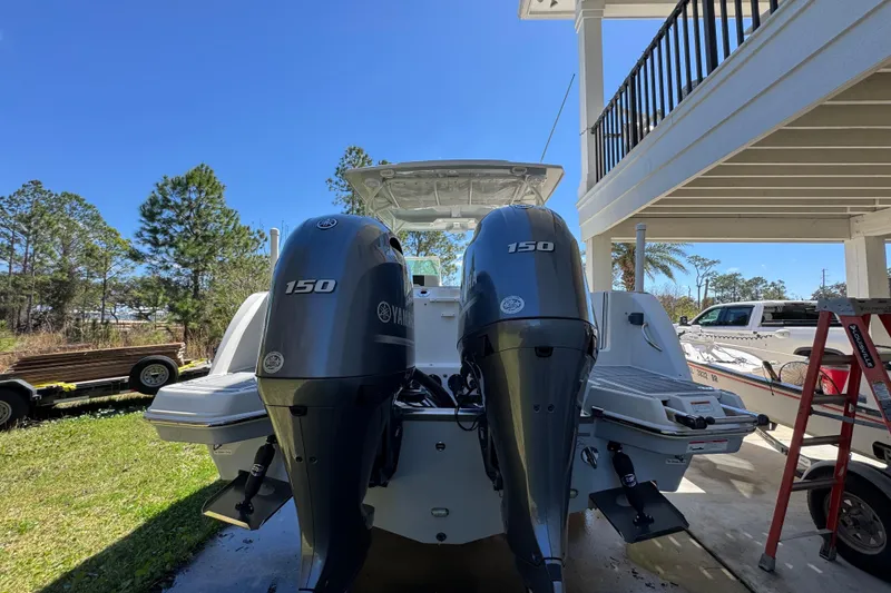 Slide: The Image of 2022 Sailfish 276 DC boat with dual Yamaha 150 engines, parked outdoors. - 12