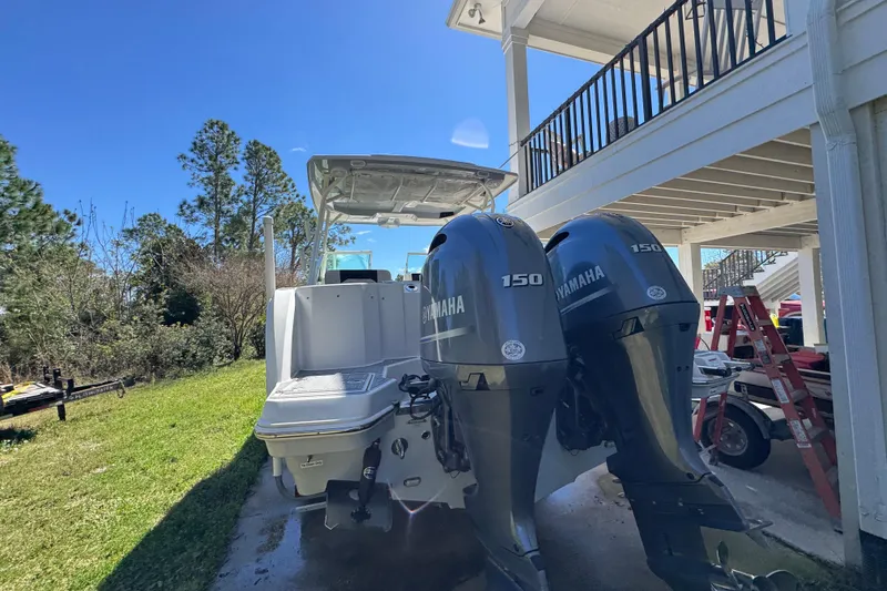 Slide: The Image of 2022 Sailfish 276 DC boat with dual Yamaha 150 engines, parked outdoors. - 13