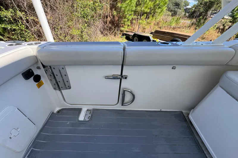 Slide: The Image of 2022 Sailfish 276 DC boat interior with cushioned seating and door, surrounded by greenery. - 31