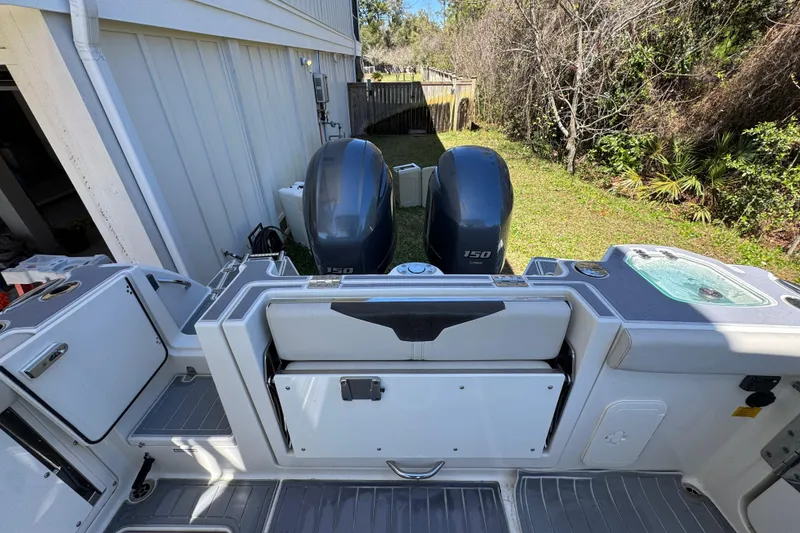 Slide: The Image of 2022 Sailfish 276 DC boat with dual 150 horsepower engines, docked near a house. - 34