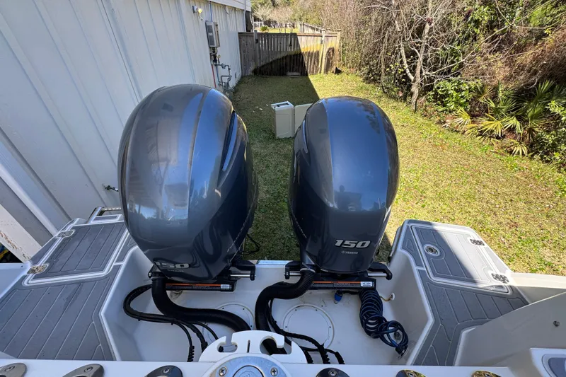 Slide: The Image of Twin Yamaha 150 outboard engines on a 2022 Sailfish 276 DC boat, parked in a grassy yard. - 36