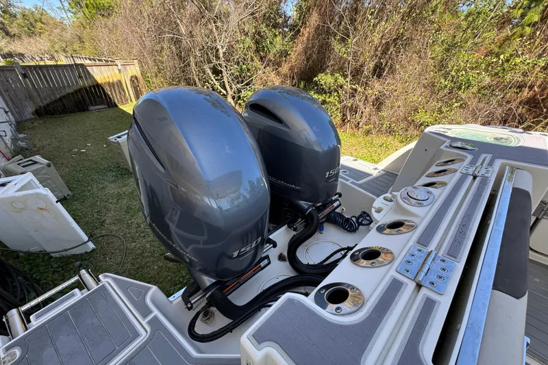 Slide: The Image of Twin outboard motors on a 2022 Sailfish 276 DC boat, parked in a grassy yard. - 38