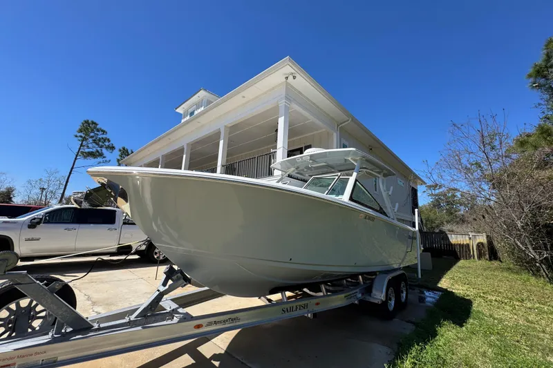 Slide: The Image of 2022 Sailfish 276 DC boat on trailer, parked beside a house under clear blue sky. - 4