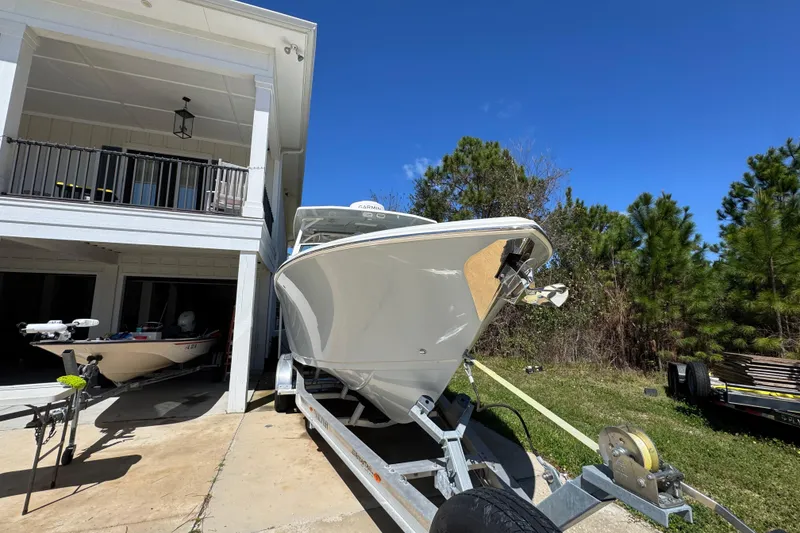 Slide: The Image of 2022 Sailfish 276 DC boat on trailer, parked beside a house under clear blue sky. - 7