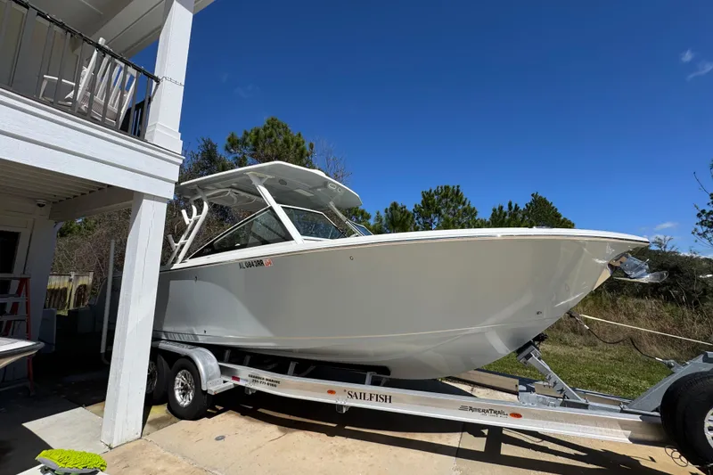 Slide: The Image of 2022 Sailfish 276 DC boat on trailer, parked outdoors under clear blue sky. - 9