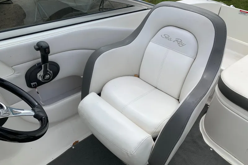 Slide: The Image of Captain's seat of 2012 Sea Ray 200 Sundeck boat, featuring white upholstery and steering controls. - 16