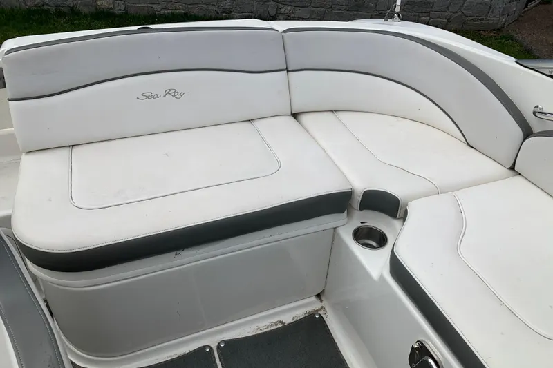 Slide: The Image of 2012 Sea Ray 200 Sundeck interior seating with white upholstery and cup holder. - 22
