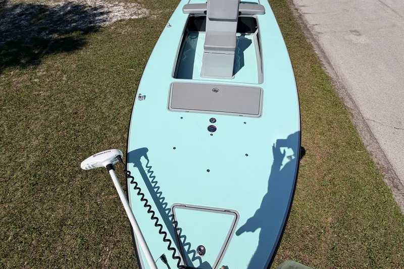 Slide: The Image of 2022 Chittum Skiffs Islamorada 21 boat on grass, featuring a sleek design and trolling motor. - 14