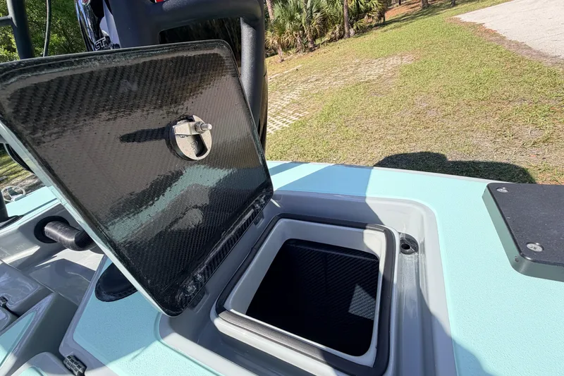 Slide: The Image of Open storage compartment on 2022 Chittum Skiffs Islamorada 21 boat, showcasing carbon fiber lid. - 49