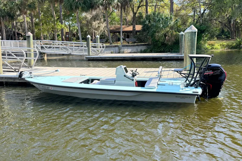 Slide: The Image of 2022 Chittum Skiffs Islamorada 21 boat docked on a calm waterway. - 90