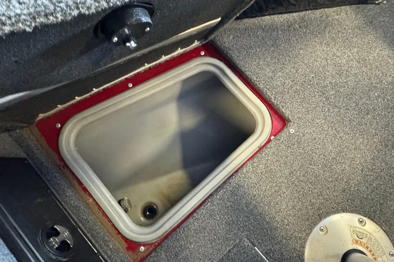 Slide: The Image of 2019 Tracker Targa V-18 WT boat storage compartment with gray carpeted interior. - 16