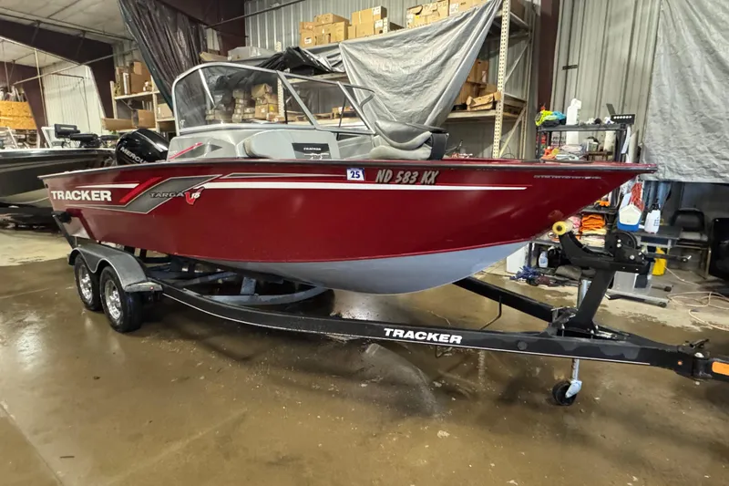 Slide: The Image of 2019 Tracker Targa V-18 WT boat in a garage, red exterior, on a trailer. - 2