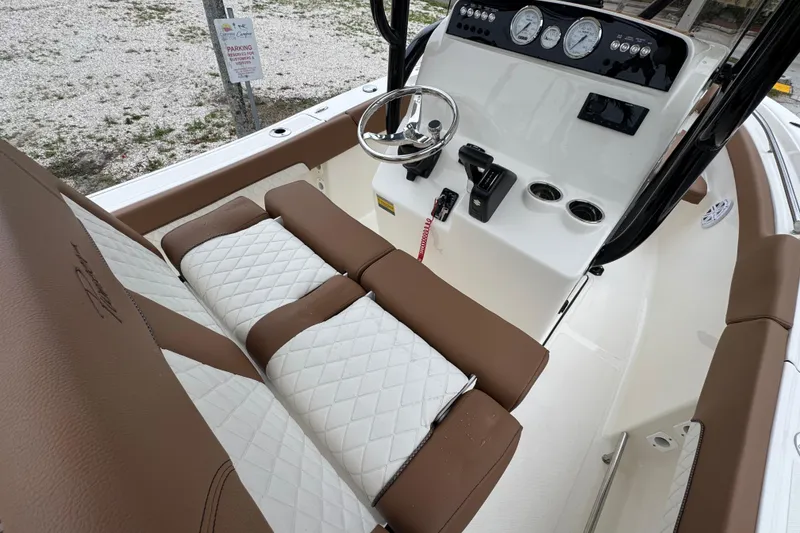 Slide: The Image of 2026 Pioneer 202 Sportfish boat interior with brown and white seating, steering console, and gauges. - 9