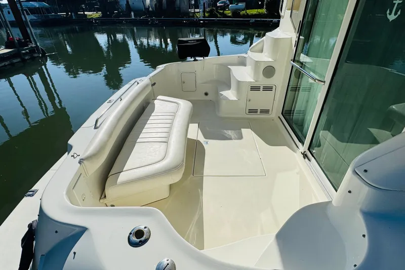 Slide: The Image of 2000 Sea Ray 400 Sedan Bridge boat deck with seating and steps, docked by calm water. - 13