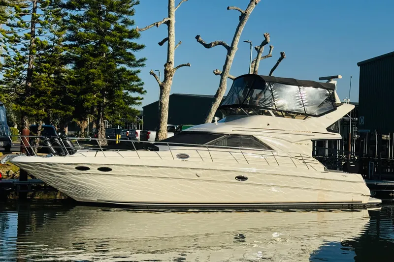 Slide: The Image of 2000 Sea Ray 400 Sedan Bridge yacht docked by trees and buildings. - 2