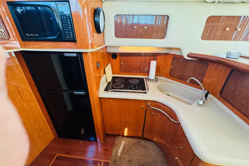 Slide: The Image of Kitchen area of 2000 Sea Ray 400 Sedan Bridge with stove, sink, and microwave. - 37