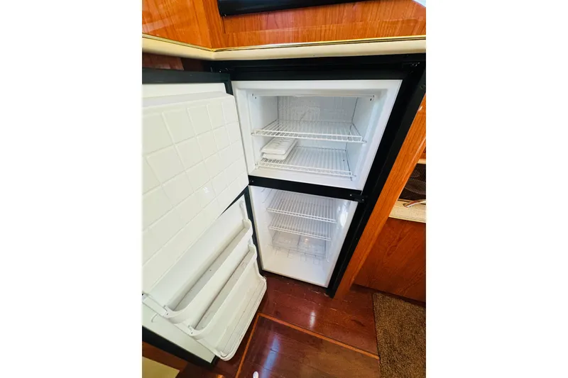 Slide: The Image of Open refrigerator inside 2000 Sea Ray 400 Sedan Bridge yacht, showcasing interior shelves. - 40