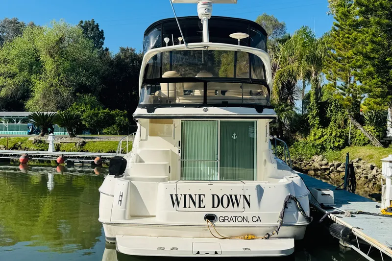 Slide: The Image of Sea Ray 400 Sedan Bridge 2000 yacht docked, named "Wine Down," in a lush marina setting. - 6