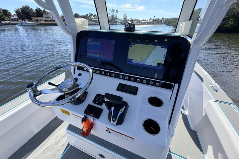 Slide: The Image of 2022 Sportsman Masters 247 Bay Boat dashboard with navigation screens and steering wheel. - 13