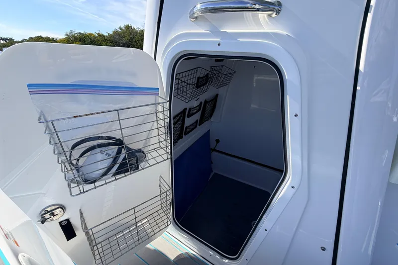 Slide: The Image of 2022 Sportsman Masters 247 Bay Boat storage compartment with wire racks and organized interior. - 18