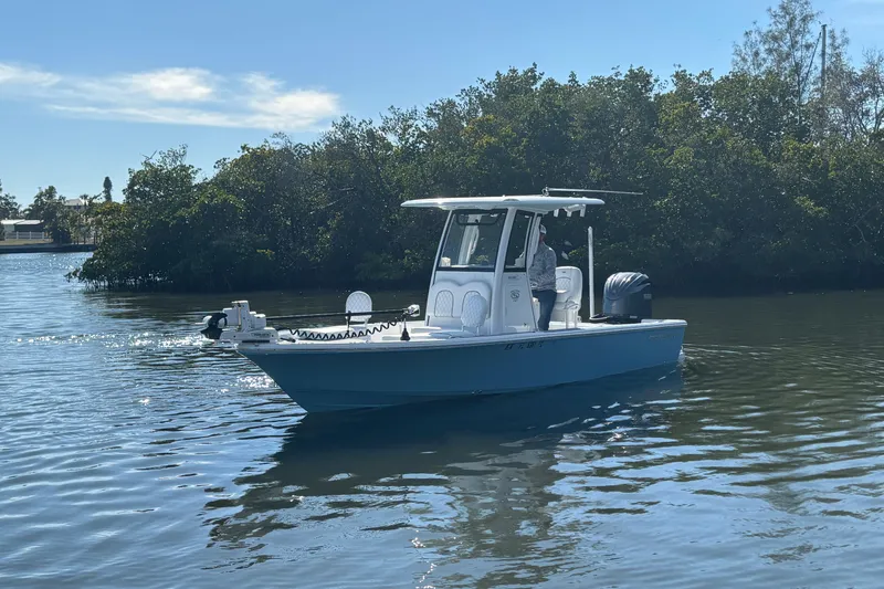 Slide: The Image of 2022 Sportsman Masters 247 Bay Boat cruising on calm water near lush greenery. - 4