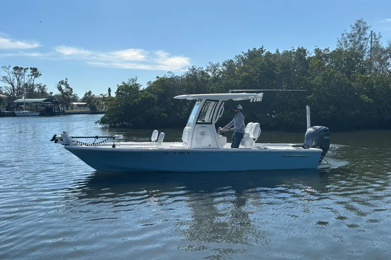 Slide: The Image of 2022 Sportsman Masters 247 Bay Boat on calm water, with a person at the helm. - 5
