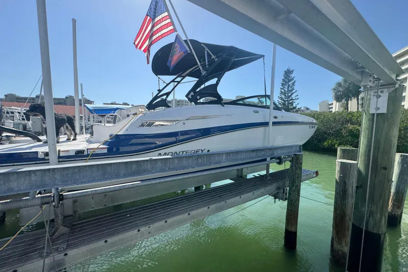 The Image of 2019 Monterey M-65 boat on lift, American flag, sunny marina setting. - 0
