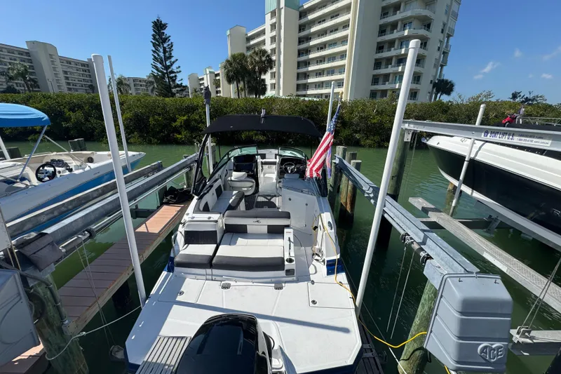 Slide: The Image of 2019 Monterey M-65 boat docked near waterfront buildings, featuring spacious seating and American flag. - 15