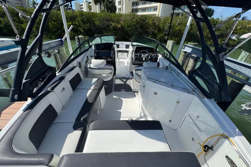 Slide: The Image of 2019 Monterey M-65 boat interior with seating and helm, docked by lush greenery. - 17