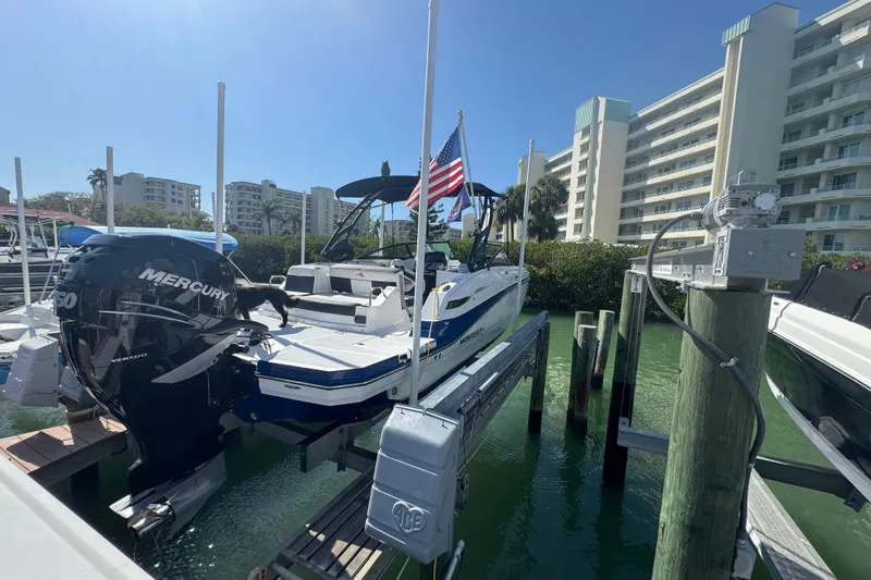 Slide: The Image of 2019 Monterey M-65 boat docked with Mercury engine, American flag, and waterfront buildings. - 2