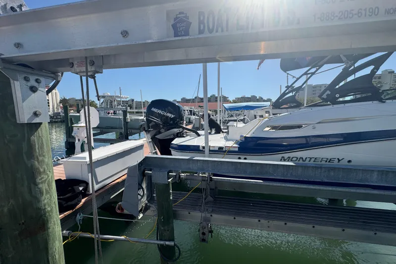 Slide: The Image of 2019 Monterey M-65 boat on lift at marina, sunny day, Mercury engine visible. - 7