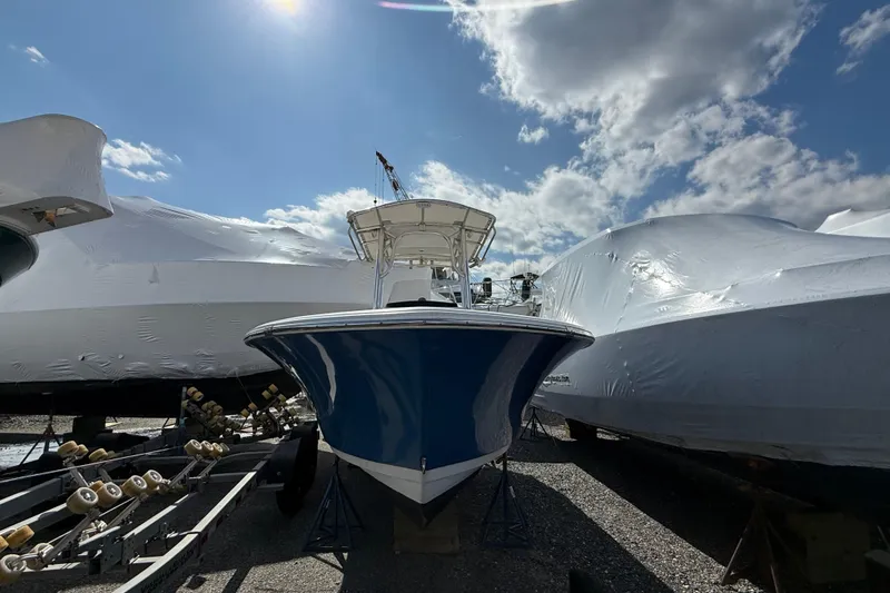 The Image of 2015 Sportsman Open 212 Center Console boat under a bright sky, surrounded by covered vessels. - 0
