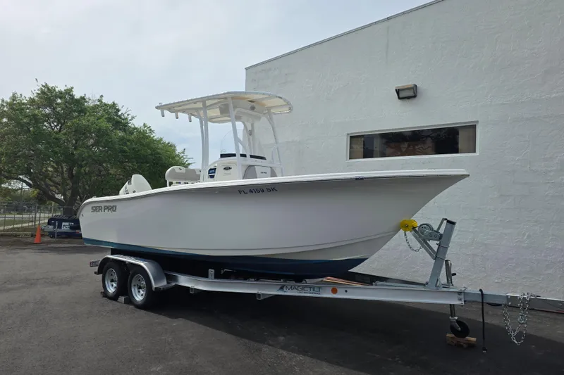 The Image of 2018 Sea Pro 219 Center Console boat on trailer, parked near a white building. - 1