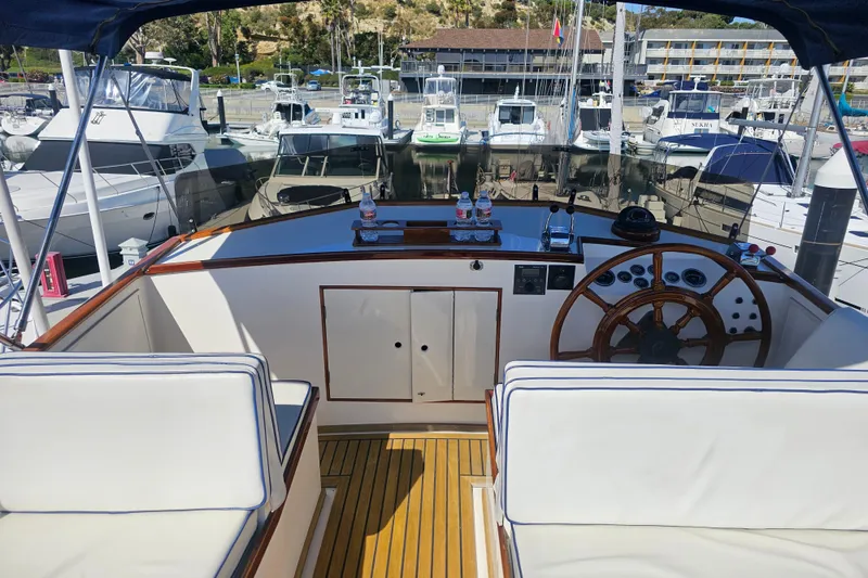 Slide: The Image of Cockpit of a 1978 Grand Banks 42 Classic yacht, featuring a wooden steering wheel and marina view. - 6