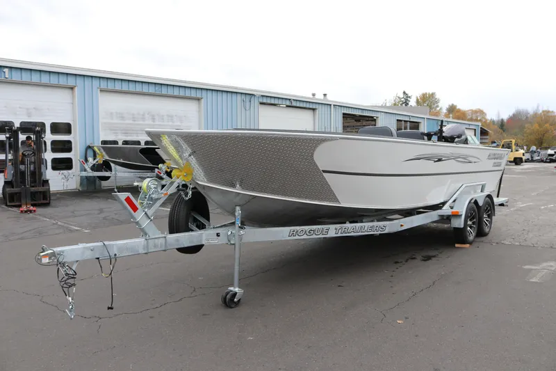 Slide: The Image of 2026 Alumaweld Columbia 23 boat on Rogue trailer, parked outside a garage. - 25