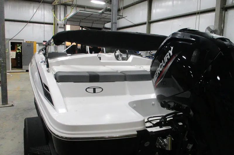Slide: The Image of 2025 Tahoe T18 boat with Mercury engine in a warehouse setting. - 2