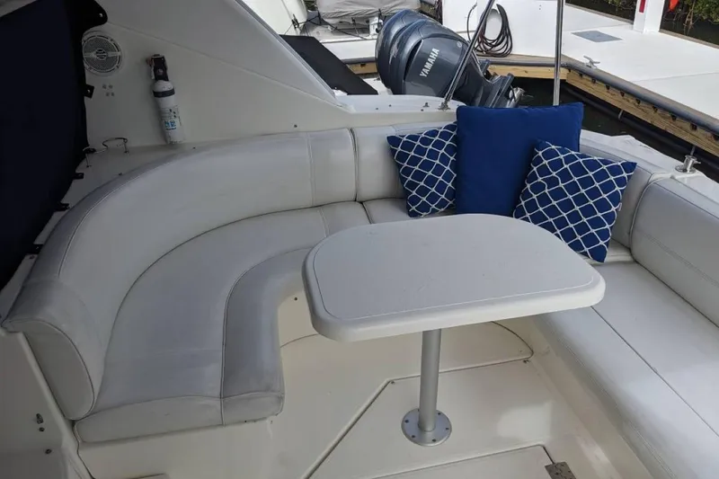 Slide: The Image of 2003 Cruisers 3970 yacht interior with white seating, table, and blue decorative pillows. - 6