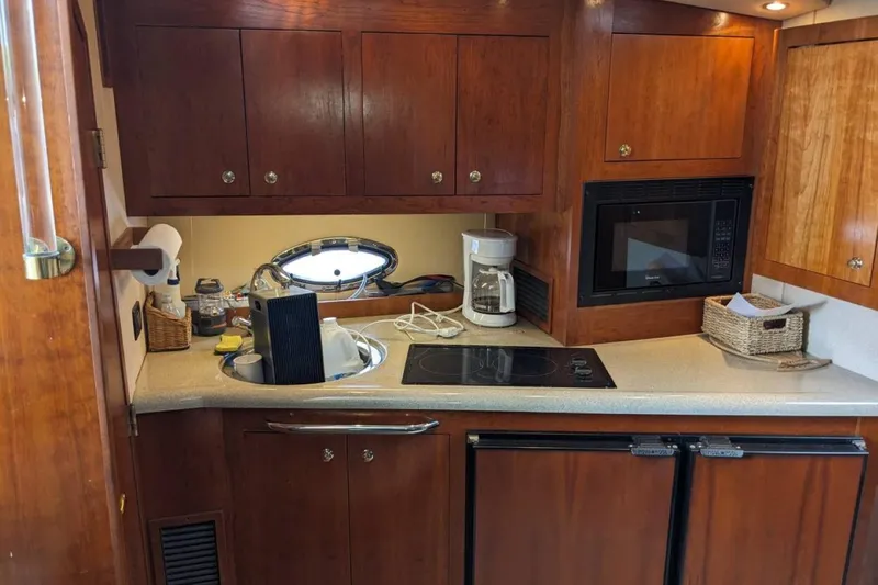 Slide: The Image of 2003 Cruisers 3970 yacht kitchen with wooden cabinets, stove, microwave, and coffee maker. - 9