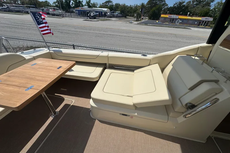 Slide: The Image of Luxurious seating area on 2026 Chris-Craft Calypso 32 boat with wooden table and American flag. - 27