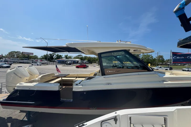 Slide: The Image of 2026 Chris-Craft Calypso 32 boat with dual Mercury engines, docked under clear blue sky. - 38